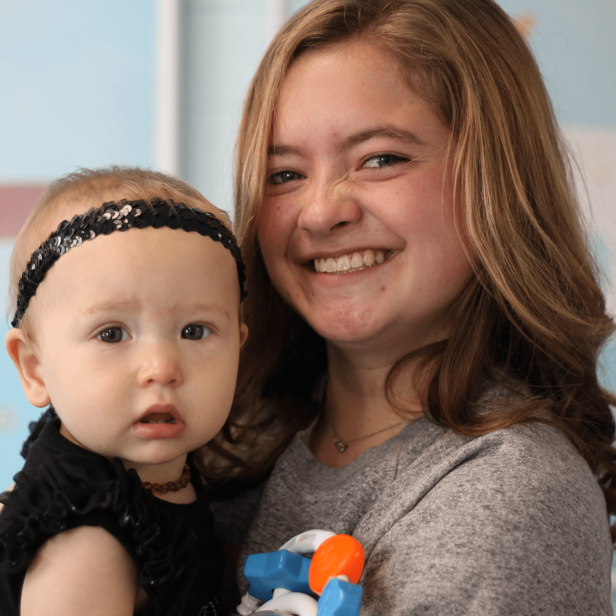 Smiling young female volunteer holding an infant at Anderson Hills Church's nursery