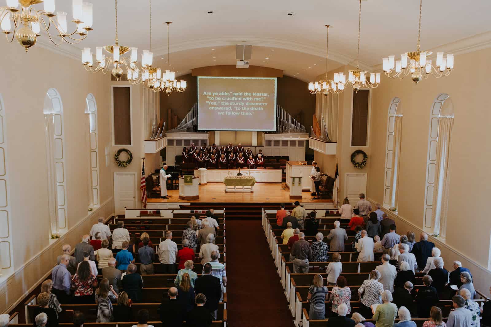 Congregation participating in Sunday service at Anderson Hills Church with choir singing on stage and sermon presented on a large screen