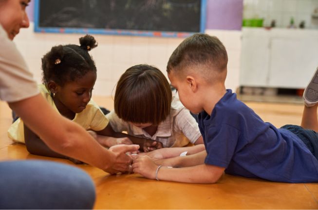 Engaged children with an Anderson Hills Church volunteer playing together on the floor during a Sunday school class