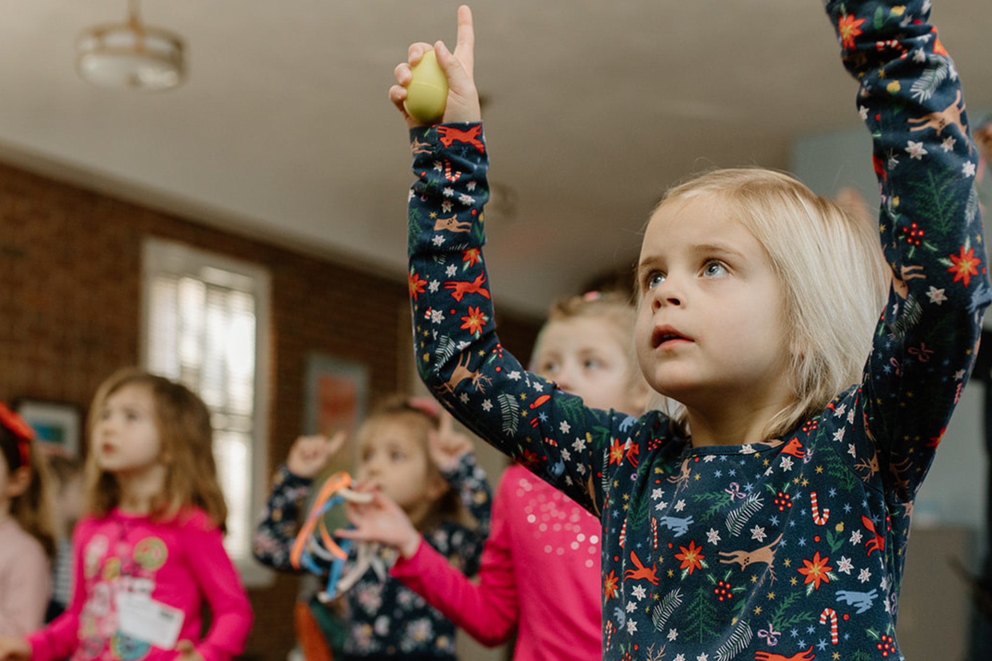 kid holding tennis ball on an activity rising both hands